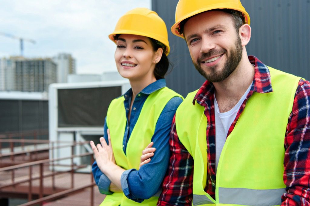 Two people wearing hard hats and vests posing for a picture.