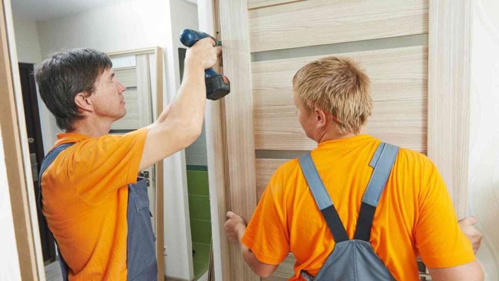 A man and boy are working on the door of their home.
